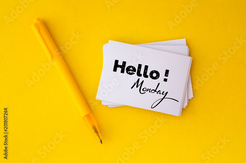 the yellow pen and stacking of  white business card with Hello Monday message on vibrant yellow background , cheerful for happy working time  Monday concept photo