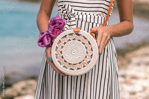 Woman with fashionable stylish rattan bag and silk scarf outside. Tropical island of Bali, Indonesia. Rattan handbag and silk scarf. photo