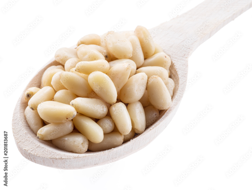 Pine nuts in the wooden scoop. White background. Pine nuts in the wooden scoop. White background.