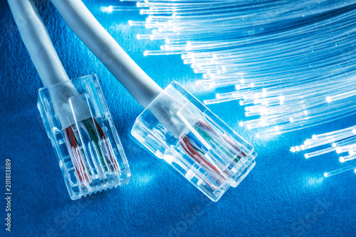 Network cables and bundle of optical fibers with lights in the ends. Blue background.