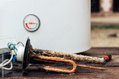 Fotografie heating element, rust and scale on boiler background, lying on wooden table