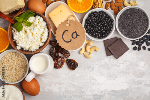 Healthy food nutrition dieting concept. Assortment of high calcium sources. Dairy products, legumes, eggs, nuts, chocolate, poppy, sesame, chocolate. White background, top view, copy space