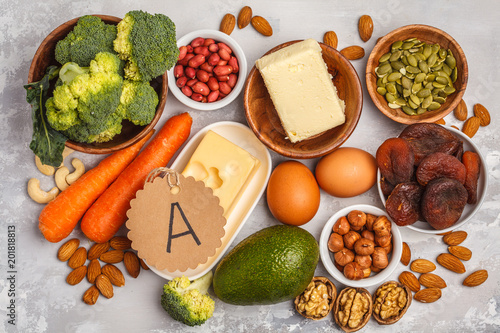 Healthy food nutrition dieting concept. Assortment of high vitamin A sources. Carrots, nuts, broccoli, butter, cheese, avocado, apricots, seeds, eggs. White background, top view