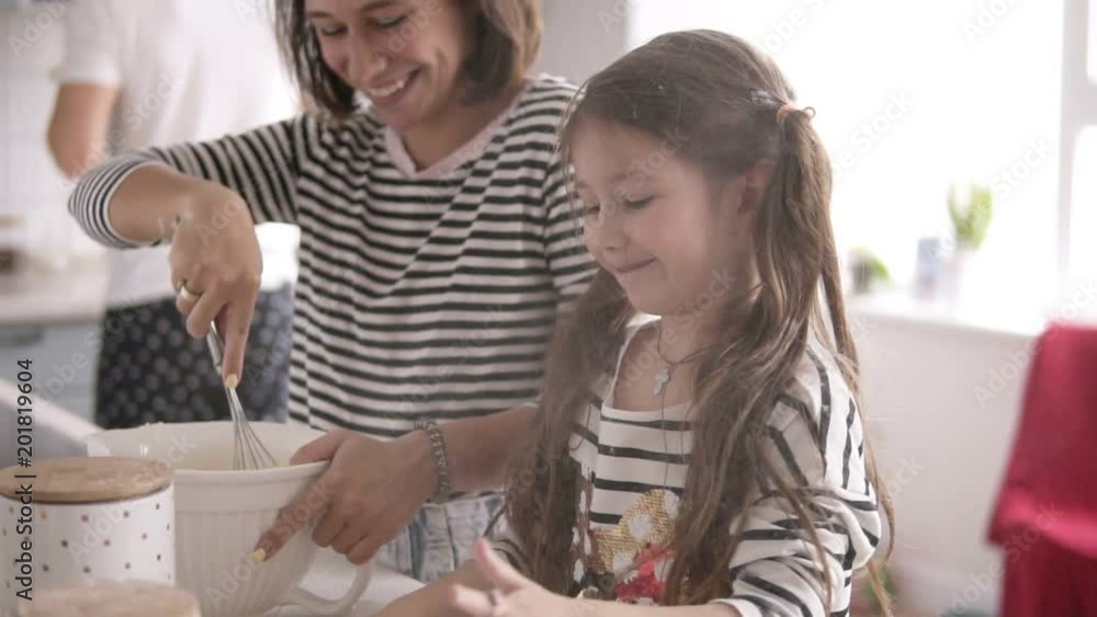 Daughter throws flour and mother is kneading the dough on the kitchen Daughter throws flour and mother is kneading the dough on the kitchen