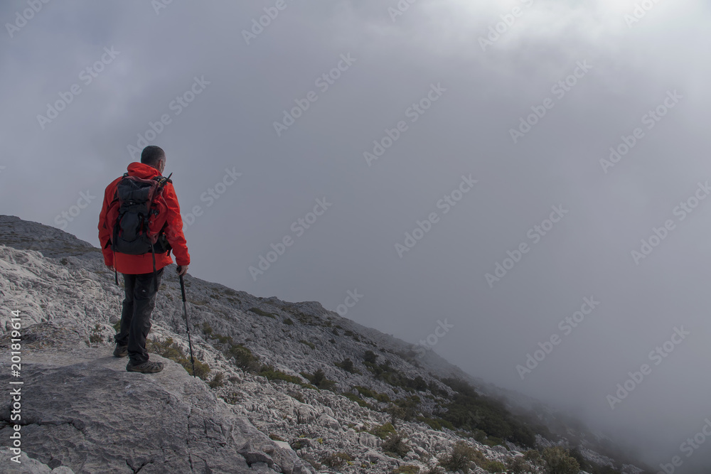 hombre que camina por la cima de una montaña entre la niebla