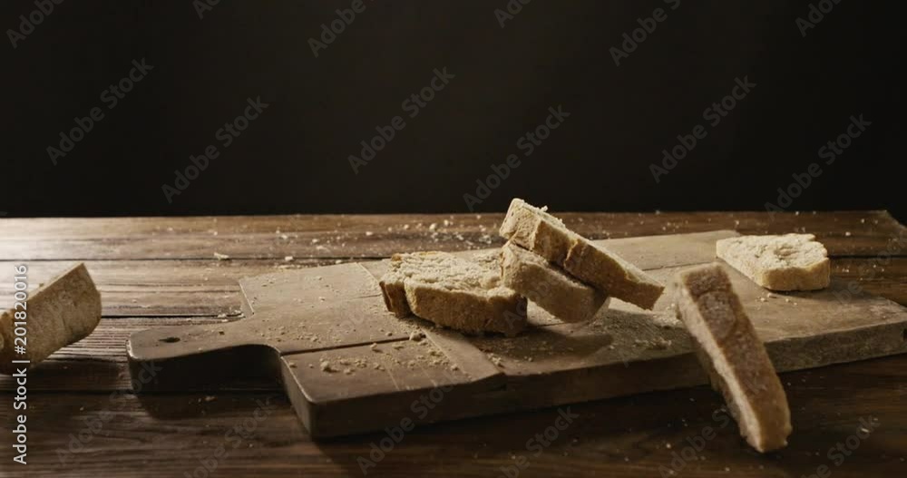 On a cutting board and a wooden table pieces of fresh bread fall On a cutting board and a wooden table pieces of fresh bread fall