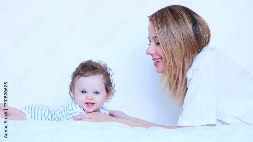 Young mother and little child boy lying down in white bed Young mother and little child boy lying down in white bed