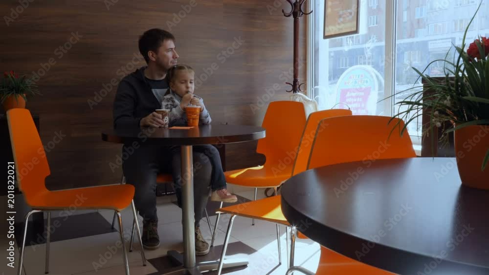 Dad and daughter are drinking coffee, a milkshake at the cafe. Dad and daughter are drinking coffee, a milkshake at the cafe.