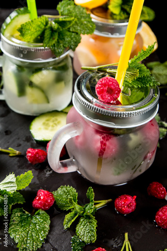 Home made mojito, Cucumber, lemon and raspberry fresh drink with fruits and vegetable on black background. 