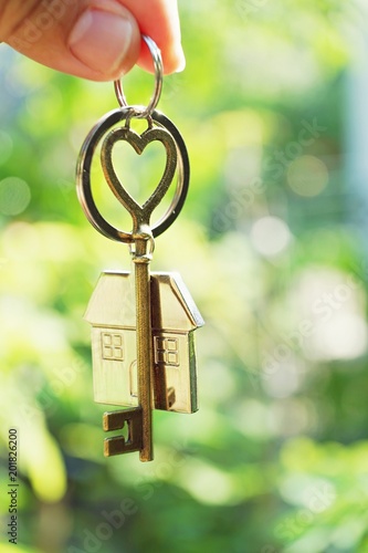 Home key with love house keyring hanging with blur garden background