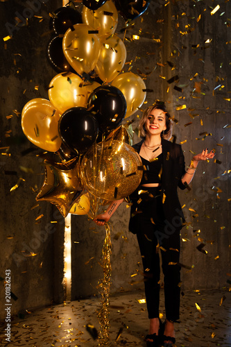Happy Girl with Balloons. Happy young girl standing with her birthday balloons, smiling. Confetti are all arounf her. She's very beautiful