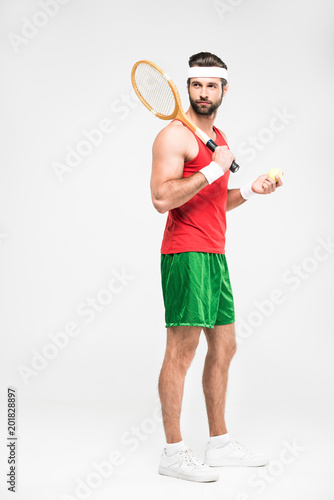 sportive tennis player posing with retro wooden racket and ball, isolated on white © LIGHTFIELD STUDIOS