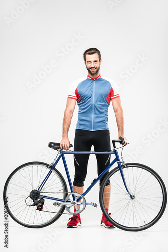 handsome cheerful cyclist in sportswear posing with bike, isolated on white