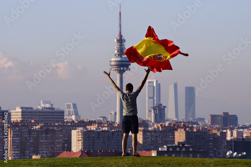 Young man throws a flag in the air, and in the background, a panoramic view of Madrid. photo