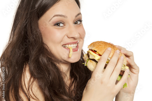 young beautiful greedy woman eating a hamburger on white background