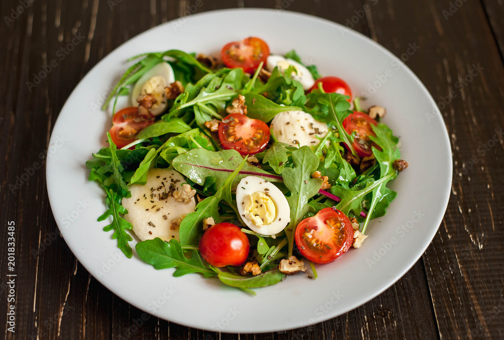 Fresh salad with tomatoes, mixed greens ,nuts, eggs, on wooden background . Healthy food.