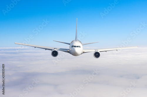 Passenger airplane flying at flight level high in the sky above overcast clouds and blue sky. View directly in front  exactly.