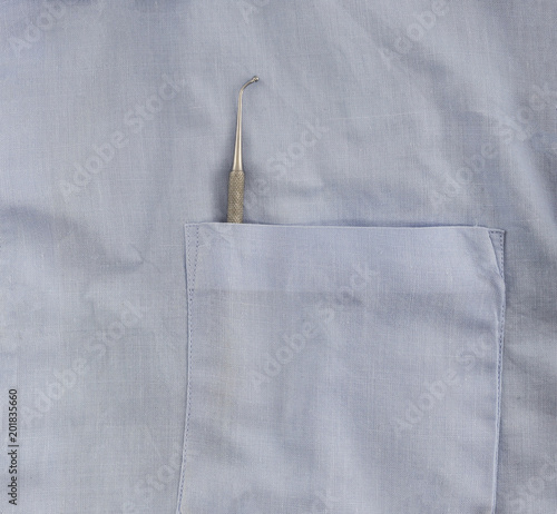 a dentist with dental instrument in the pocket of the blue lab coat