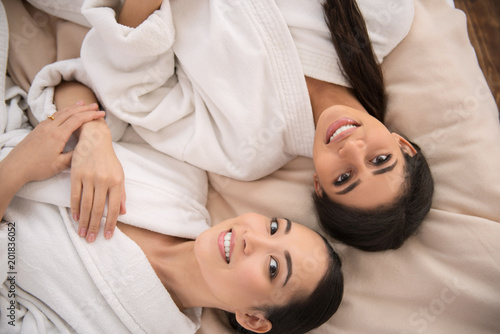 Happy female couple. Top view of beautiful young women looking at you while being in the spa salon