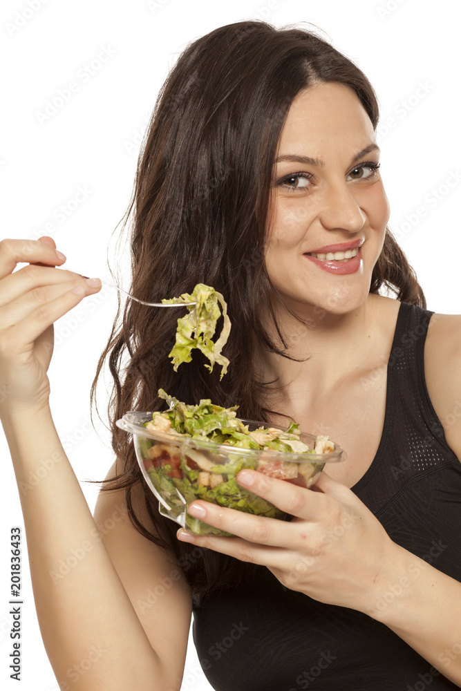 young beautiful woman eating a caaesar salad to go on white background young beautiful woman eating a caaesar salad to go on white background