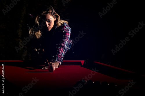 Young woman playing billiards in the dark billiard club © FS-Stock