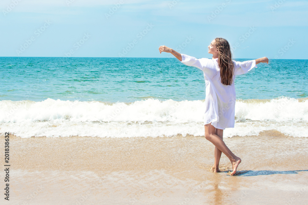 Beautiful woman relaxing and enjoying the wind in her hair, in the sound of the waves, in the smell of the ocean on the beach by the ocean Beautiful woman relaxing and enjoying the wind in her hair, in the sound of the waves, in the smell of the ocean on the beach by the ocean