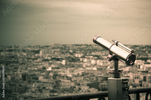 golden and silver vintage binoculars on a platform of eiffel tower with paris in background