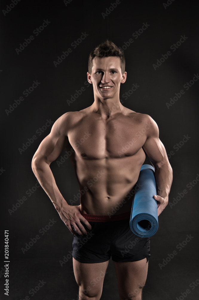 Happy man hold yoga mat. Sportsman smile with sexy torso and six pack. Athlete smiling with strong arms in shorts. Gym equipment for training and workout. Sport yoga and fitness activity, vintage