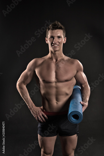 Happy man hold yoga mat. Sportsman smile with sexy torso and six pack. Athlete smiling with strong arms in shorts. Gym equipment for training and workout. Sport yoga and fitness activity, vintage © be free