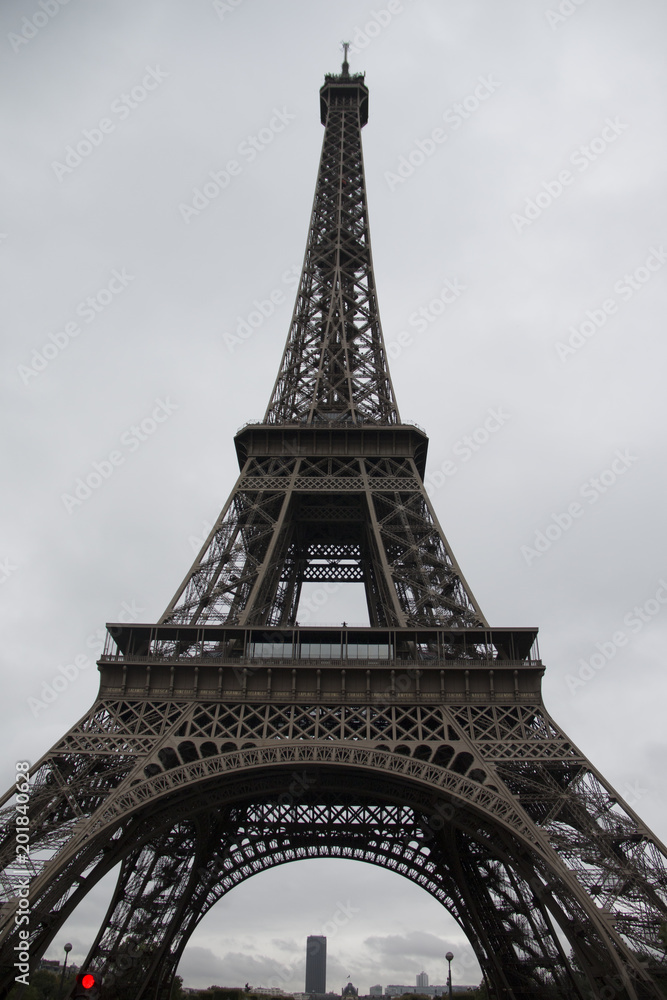 the eiffel tower from the ground up on a cloudy day with clouds and even lighted sky