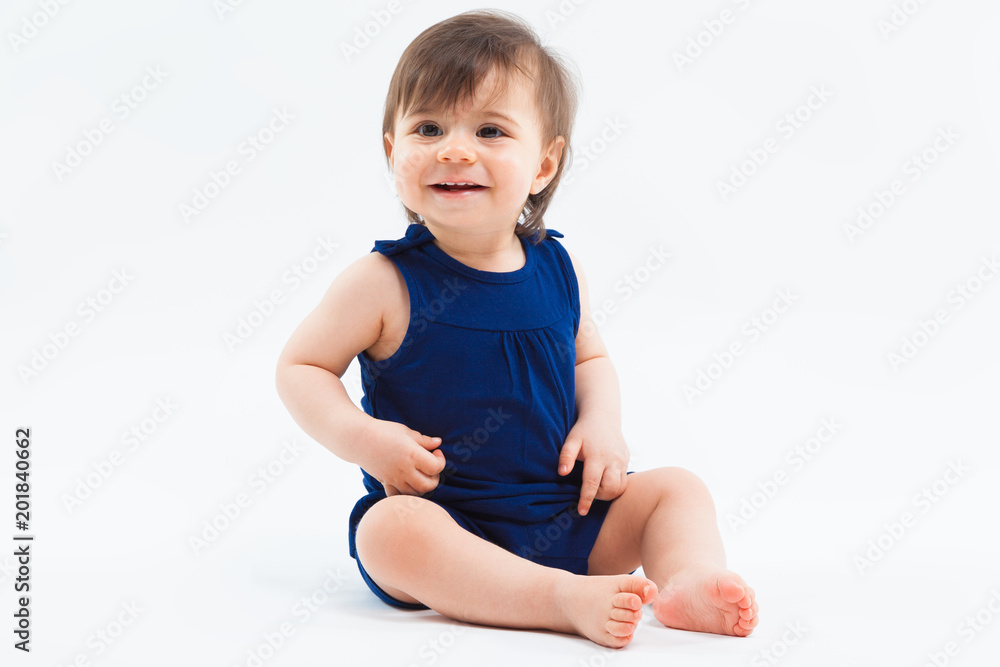 Cute funny small smiling girl sitting in studio posing on white background