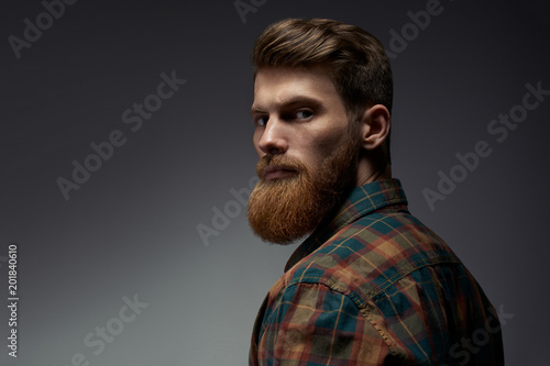 Perfect beard. Close-up of young bearded man standing against grey background