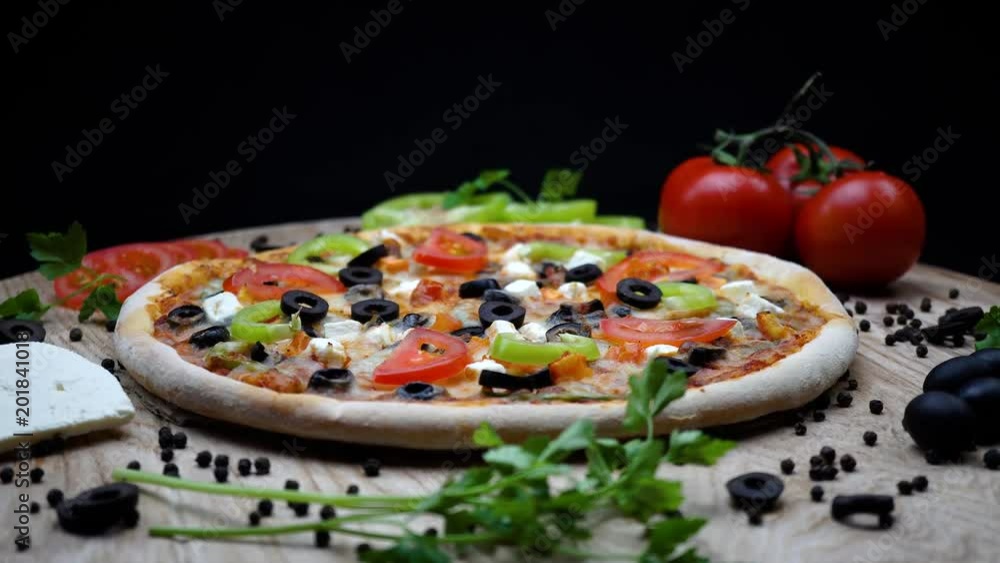 Rotating vegetable pizza with minced meat on a wooden stand isolated on a black background. 4K Rotating vegetable pizza with minced meat on a wooden stand isolated on a black background. 4K