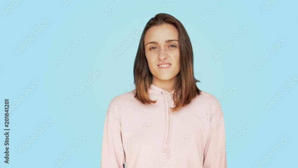 Shot with copy space on side, beautiful teenager girl or young pretty woman on colorful blue pastel background makes disgusted face expression, real emotions, grossed out