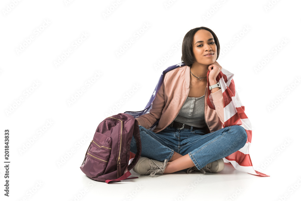 female african american student sitting on floor with backpack and american flag, isolated on white female african american student sitting on floor with backpack and american flag, isolated on white