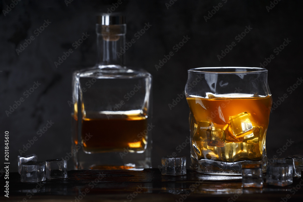 Alcohol in glass with ice and in bottle on dark background Alcohol in glass with ice and in bottle on dark background