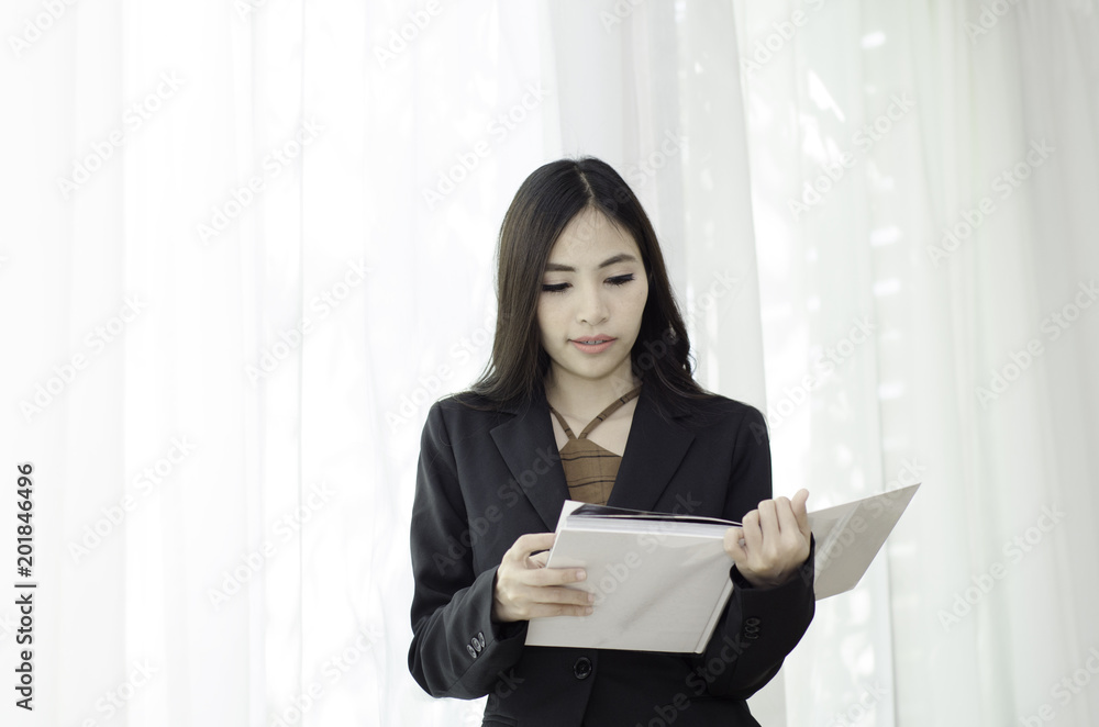 Asian women In black suit Standing holding a white book and smiling happily at work in the morning.Businesswoman standing White background,Black spots on the face of a woman caused by sunlight. Asian women In black suit Standing holding a white book and smiling happily at work in the morning.Businesswoman standing White background,Black spots on the face of a woman caused by sunlight.