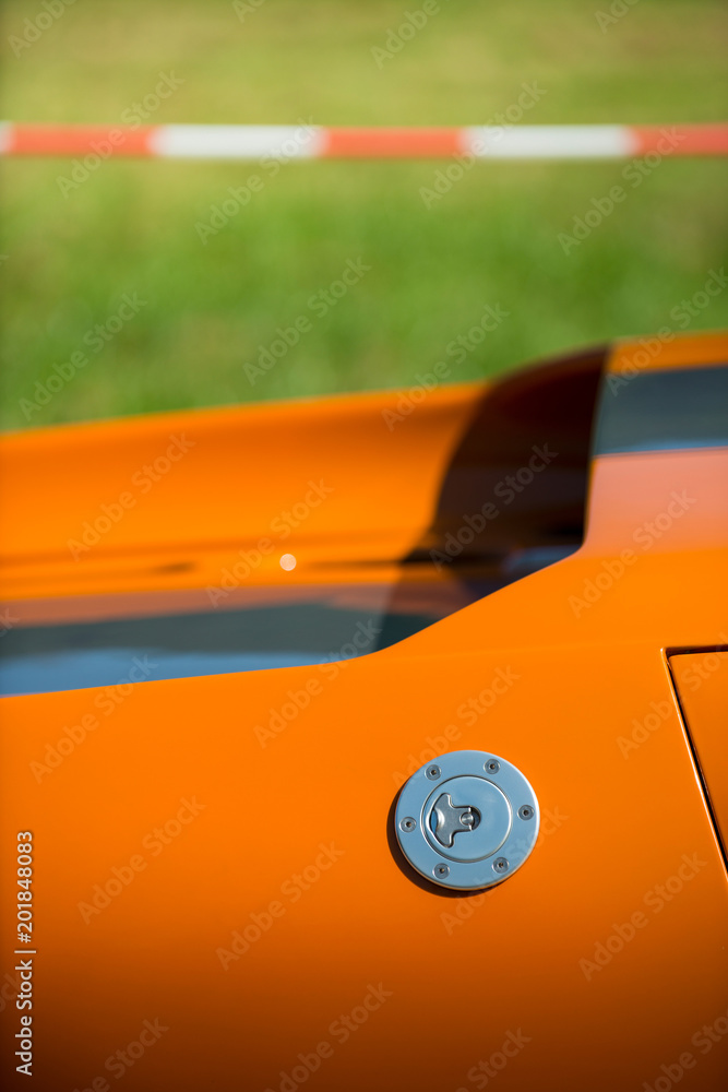 detail of a beautiful orange classic car waiting at the pit for the great race