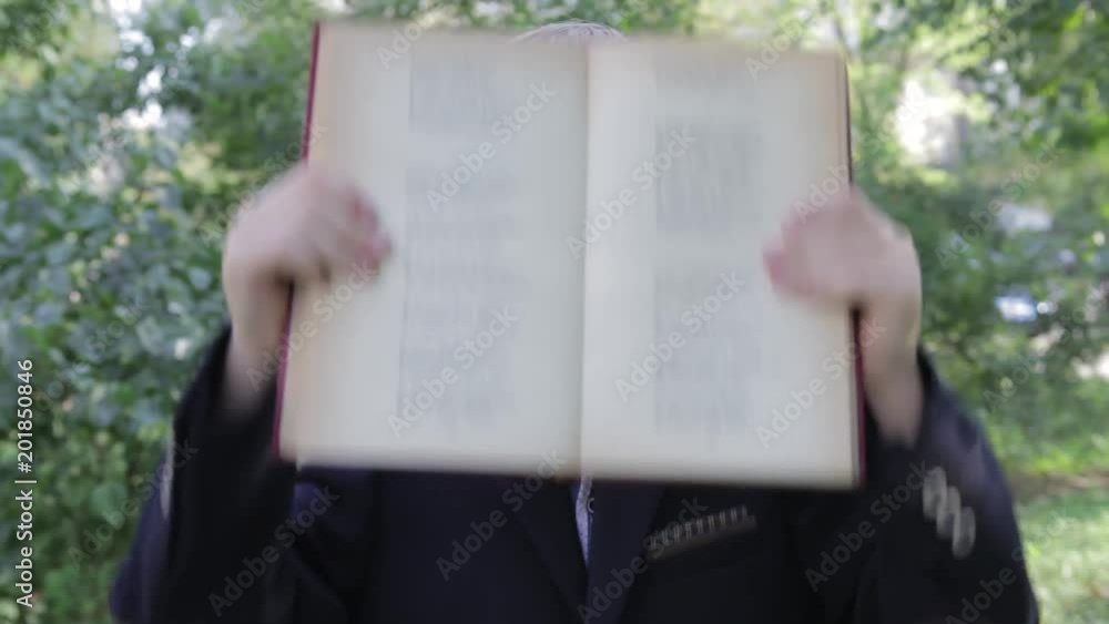 custom made wallpaper toronto digitalA boy with a book in his hands playing his face. The boy looks funny from behind the book. The boy in the jacket.
