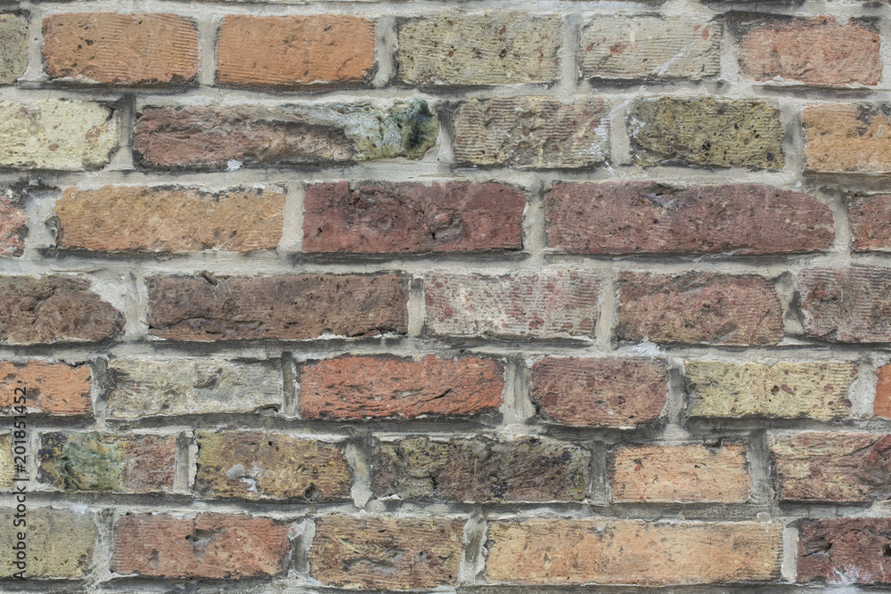 Wall made from red and sometimes colorful bricks of regular shapes and random distribution slotting together precisely. Close up architecture photography. Creative wallpaper photography.