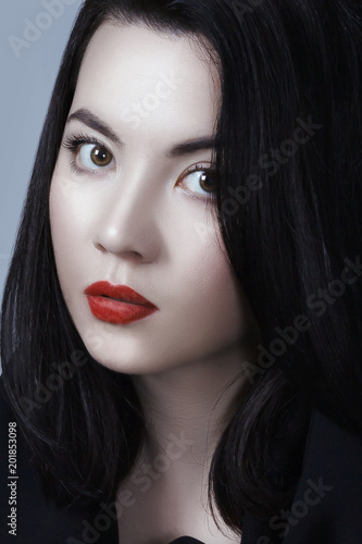 Young adult sexy lady with white skin red lips and black straight hairstyle. Mixed race Caucasian Asian female model isolated on gray background