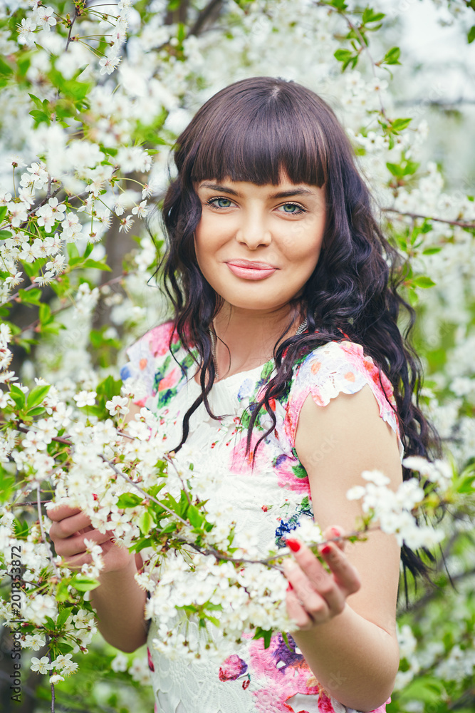 Young beautiful woman enjoying smell of blooming tree on a sunny day. Outdoor portrait in a blooming spring park Young beautiful woman enjoying smell of blooming tree on a sunny day. Outdoor portrait in a blooming spring park
