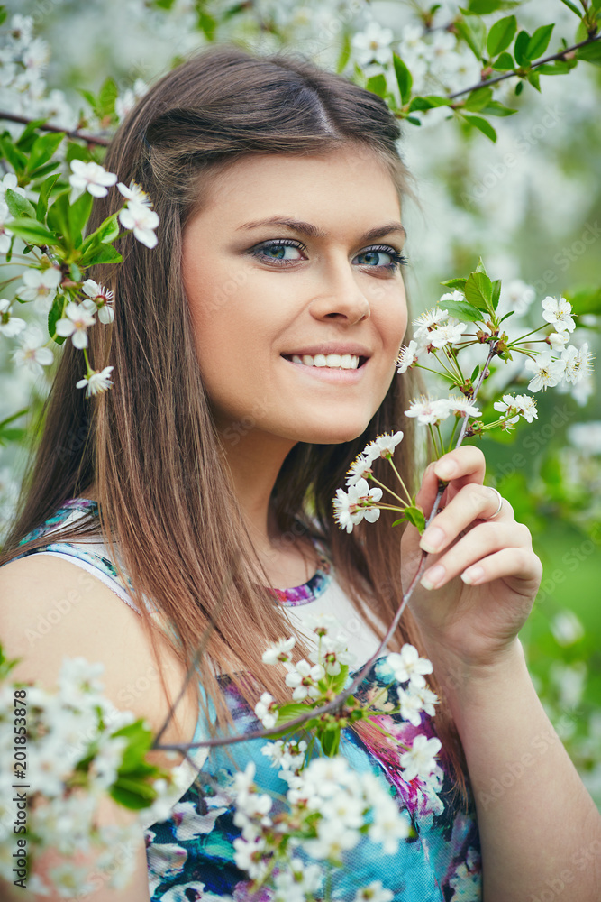 Young beautiful woman enjoying smell of blooming tree on a sunny day. Outdoor portrait in a blooming spring park Young beautiful woman enjoying smell of blooming tree on a sunny day. Outdoor portrait in a blooming spring park