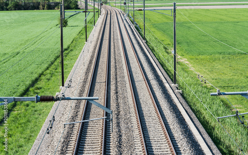 several railroad tracks leading to the horizon in midst of green fields