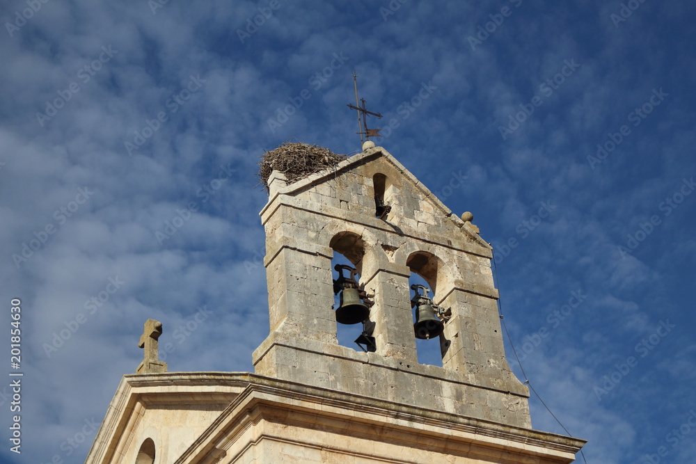 Nido de cigueña sobre la torre del campanario de una iglesia