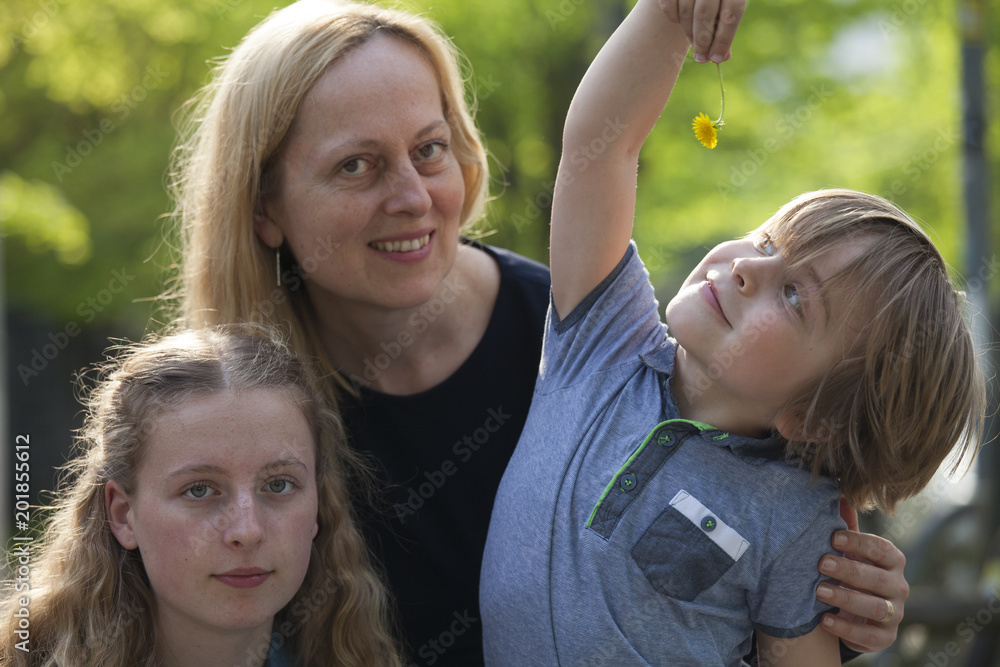 Pequeño niño sujetando una flor contento y feliz, al igual que su madre y su hermana mayor. Pequeño niño sujetando una flor contento y feliz, al igual que su madre y su hermana mayor.