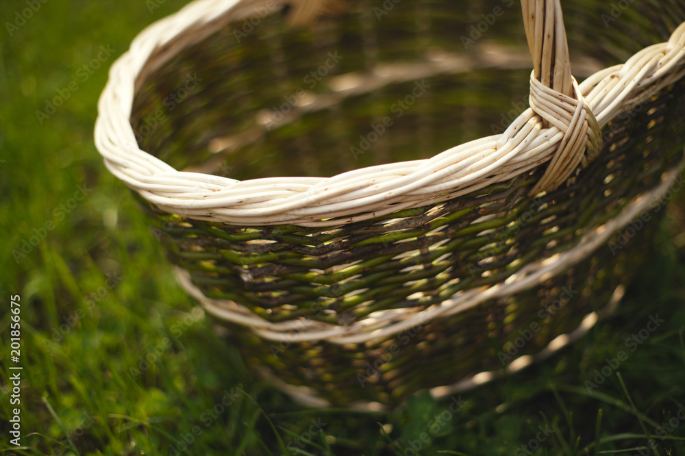 Obraz premium Wicker basket stands on a background of green grass. Tilt-shift effect.