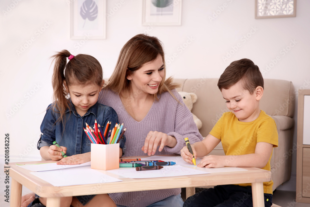 Cute little children and their nanny drawing at home Cute little children and their nanny drawing at home