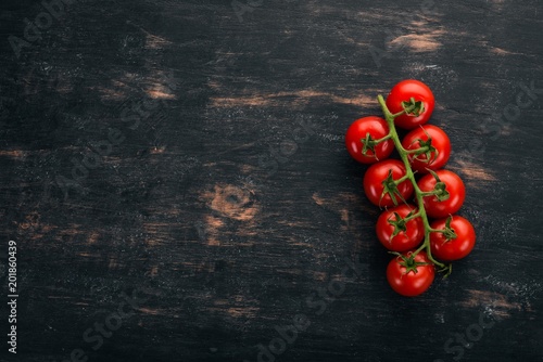 Cherry tomatoes on a twig. Top view. On a black wooden background. Copy space.