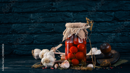 Marinated cherry tomatoes in a jar. Stocks of food. Top view. On a wooden background. Copy space.